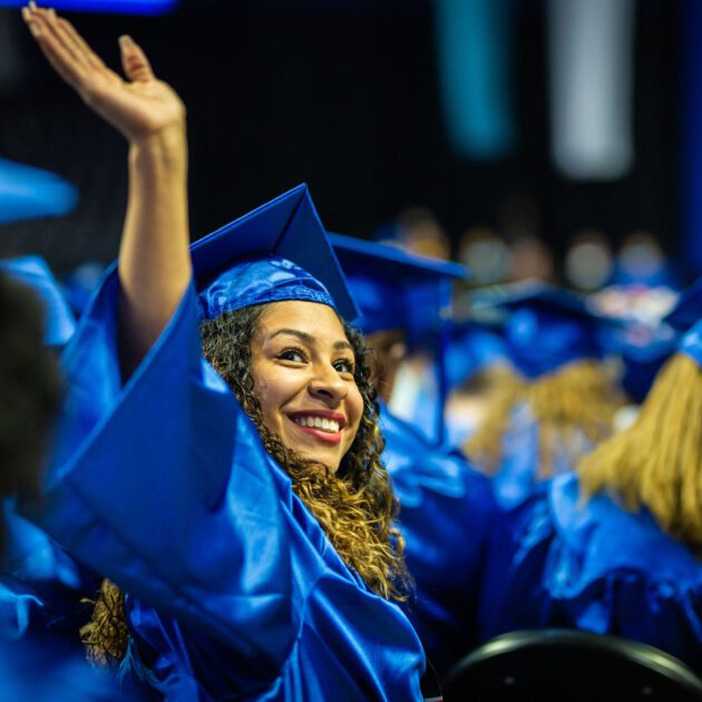 image of student at graduation smiling and waving