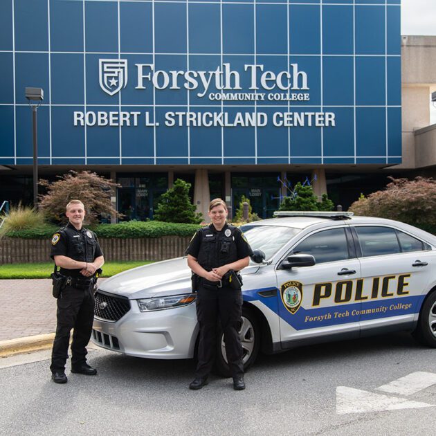 image of campus police in front of campus police car at Strickland building