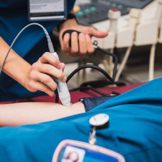 Hands operating a medical device wand and blood pressure pump on an arm