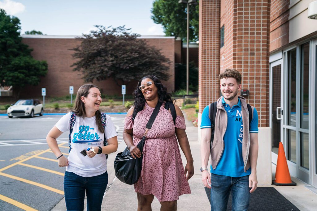 imagen de tres estudiantes sonriendo paseando al aire libre