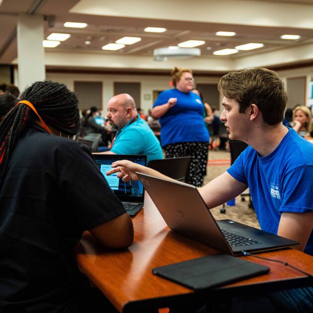 image of a staff member and a student working on laptops