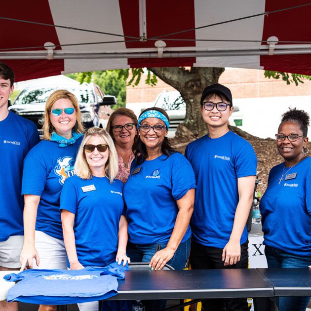 image of a group of staff wearing blue t shirts standing outside