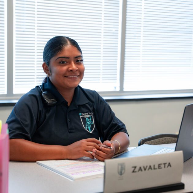 A female smiling at the camera in front of her computer