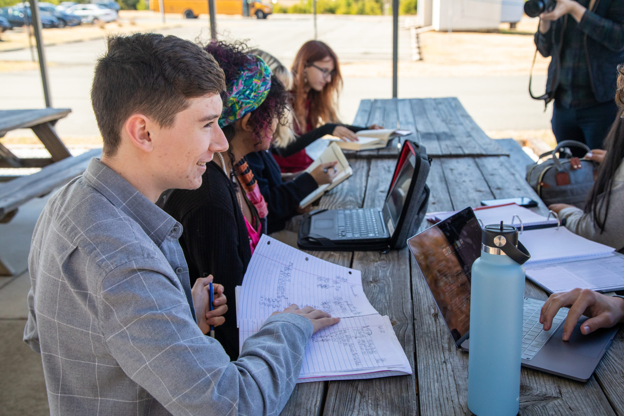 Students sitting at a picnic table studying and talking.