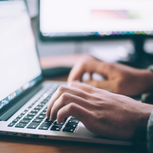 A close up image of hands typing on a computer.