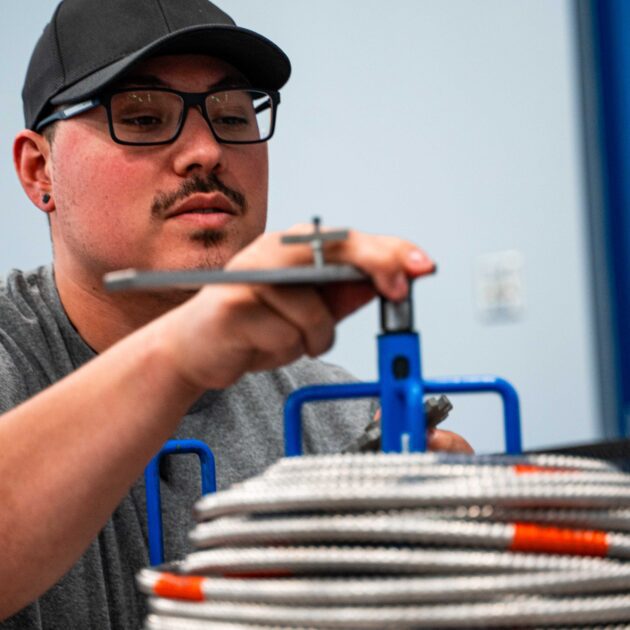 A man is looking at a cable dispenser and placing his hand on it.