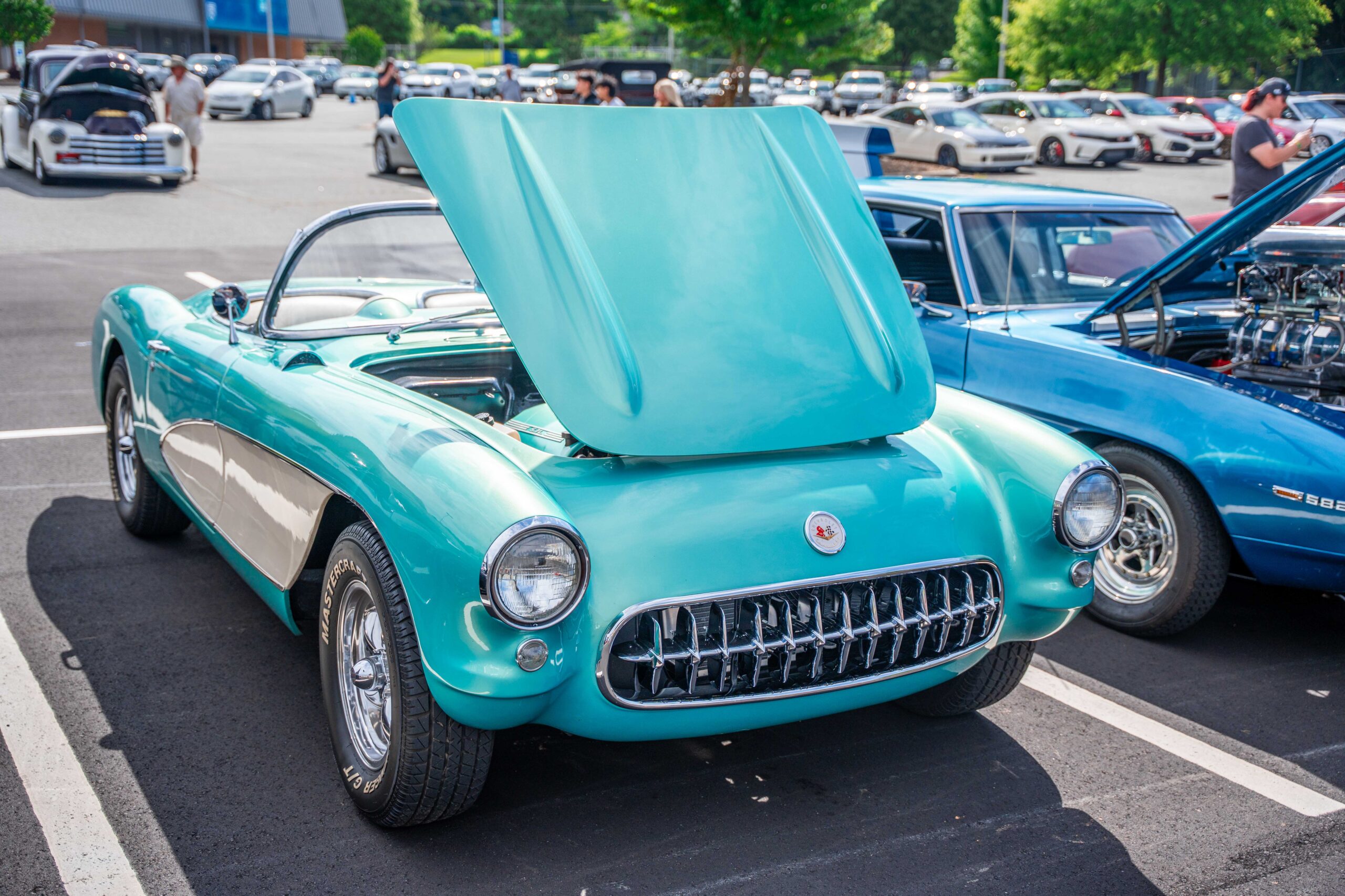 A teal blue, antique, 2-door convertible car with its hood up is outside 