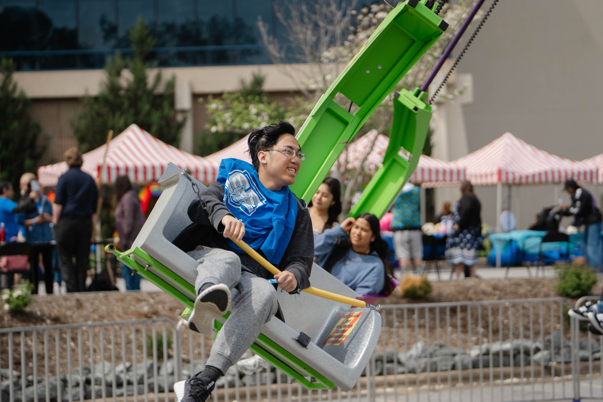 A student rides a carnival ride and is smiling.